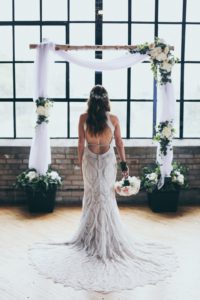 A bride in her wedding dress standing under the arch.