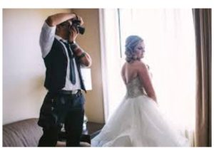 A man taking a picture of a woman in a wedding dress.
