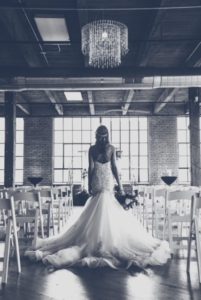 A bride in her wedding dress standing in front of chairs.